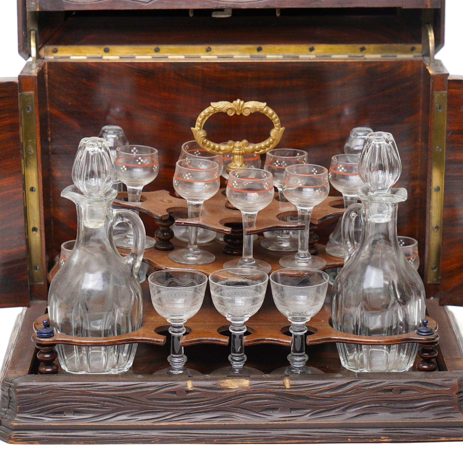 Late 19th century cave à liqueur black forest style decanter box, with carved naturalistic decoration, lifting top and fold out side panels, the interior fitted with four decanters and sixteen glasses, the smaller glasses with applied painted decoration, the others with etched design, with key, when closed overall W36cm x D29cm x H28cm 
