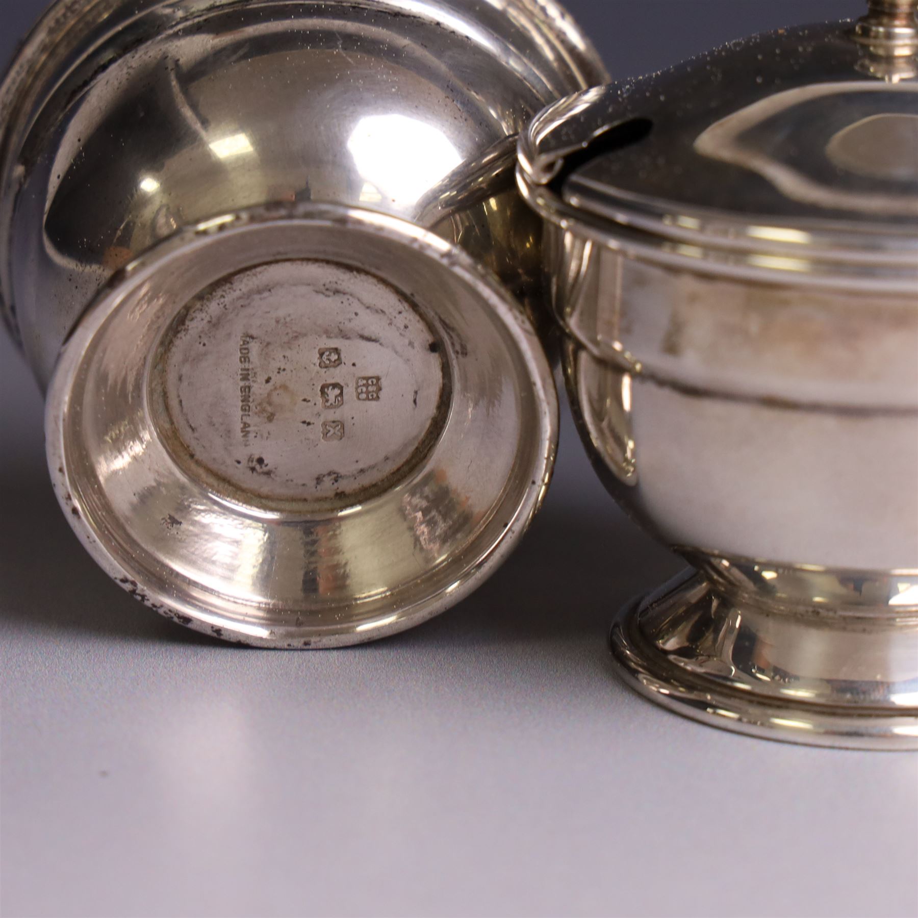 Mid 20th century silver three piece cruet set, comprising mustard pot and cover, pepper pot and open salt, hallmarked Charles S Green & Co Ltd, Birmingham 1947, with blue glass liners and two matched silver condiment spoons, contained within fitted case