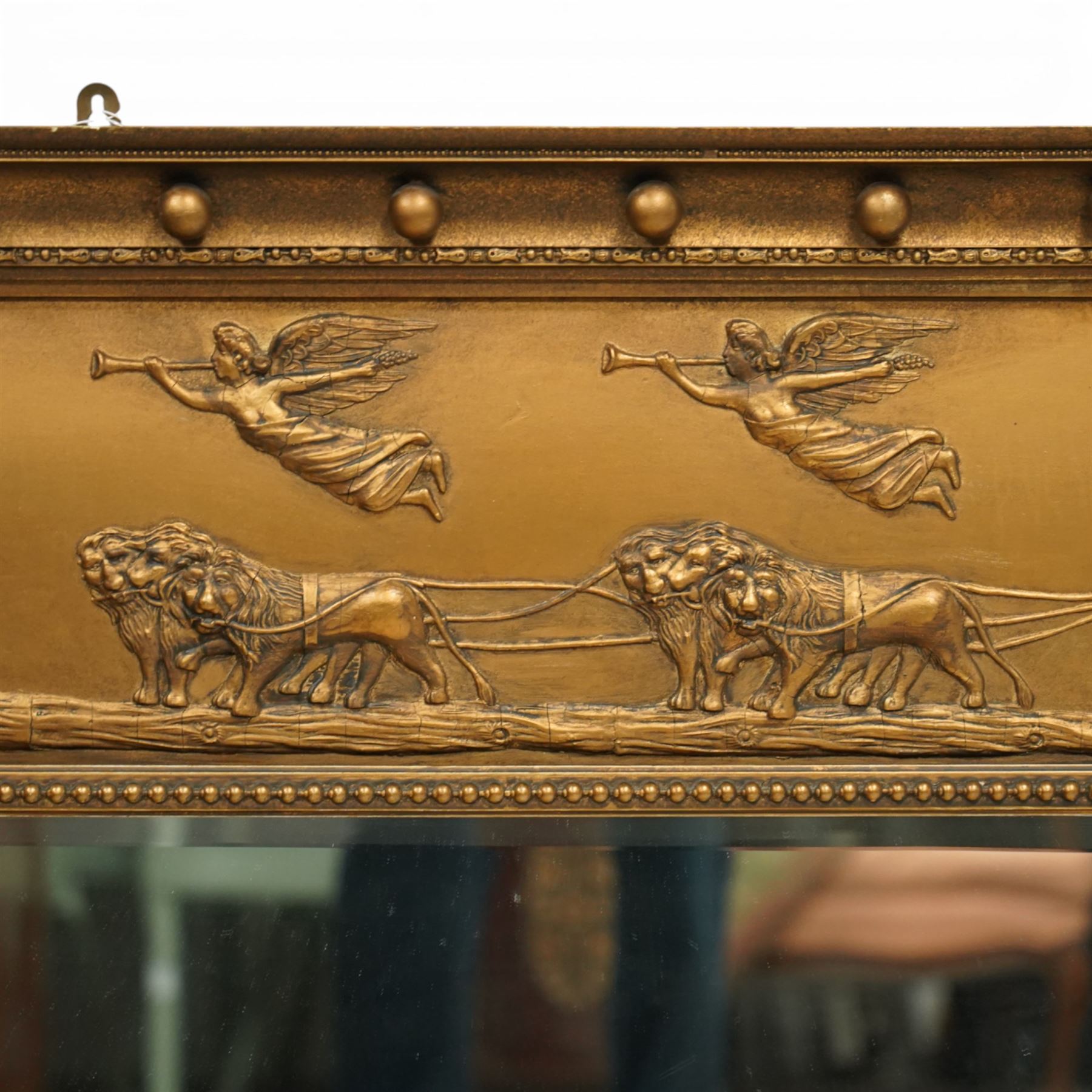 Early 20th-century giltwood tripartite overmantel mirror, rectangular frame with ball decorated cornice above frieze decorated with a classical allegorical depiction of the Triumph of Cybele in a processional chariot drawn by lions, above a beaded moulding and rectangular mirror plate, flanked by plain and reeded pilasters with Corinthian capitals, shafts decorated with pendant garlands  