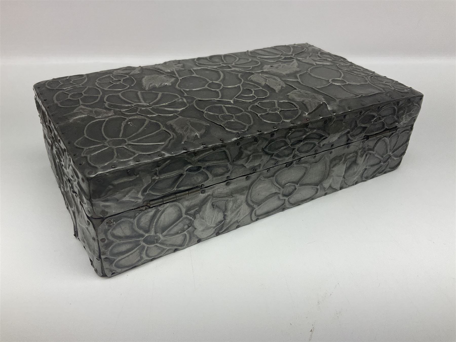 Liberty & Co Tudric pewter cigarette box, of plain rectangular form, with planished decoration to the slightly domed cover, opening to reveal a softwood interior, stamped Made in England 01234 Tudric Solkets beneath, together with another cigarette box, with applied pewter panels repousse decorated throughout with flower heads and leaves, with compartmentalised softwood interior, largest H5.5cm, W23cm