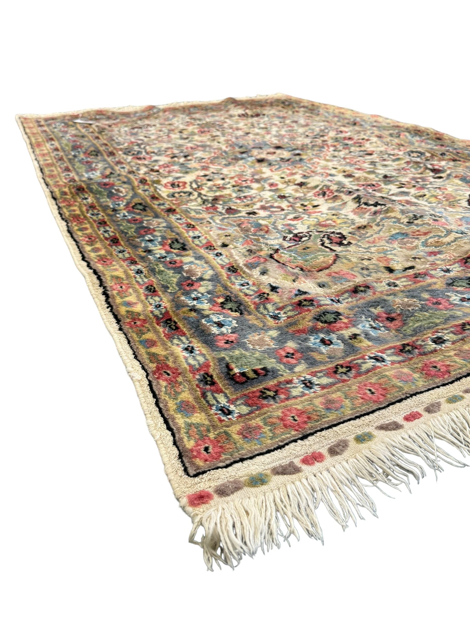 Persian design ivory ground rug, overall floral design with shaped central medallion, the main border decorated with trailing flower head pattern, within guard stipes 