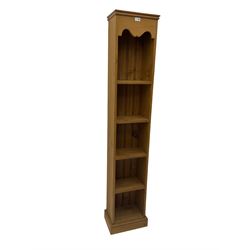Pine narrow open bookcase, shaped frieze over four shelves, on plinth base