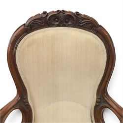 Late Victorian walnut open armchair, the carved shaped cresting rail centred by scrolls and foliage above a padded serpentine back and overstuffed seat upholstered in cream striped fabric, with padded scroll arms on open carved supports, raised on cabriole supports with carved knees and ceramic castors