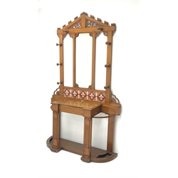  Late Victorian oak hall stand, raised tiled back with shaped and pierced pediment, rectangular mirror, eight pegs, single frieze drawer, two metal umbrella stands, W122cm, H210cm, D41cm  