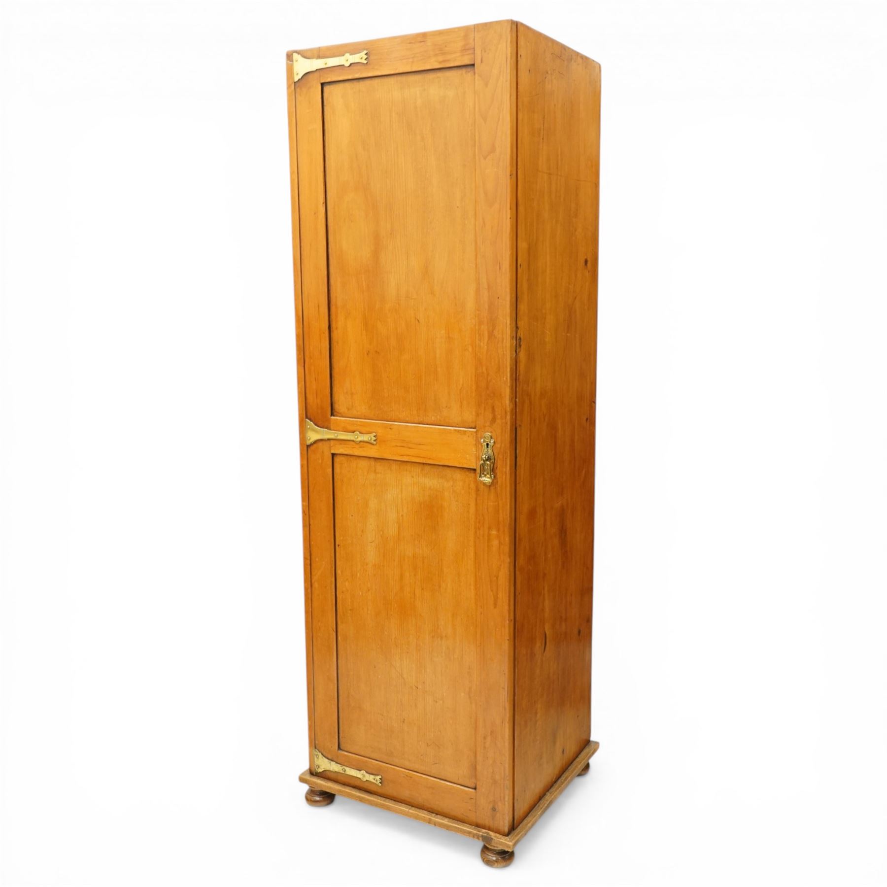Late 19th century Arts & Crafts stained pine single hall wardrobe, single panelled door with brass fittings enclosing sliding tray to top with hanging rail and hooks, hinged box seat to base, on compressed bun feet