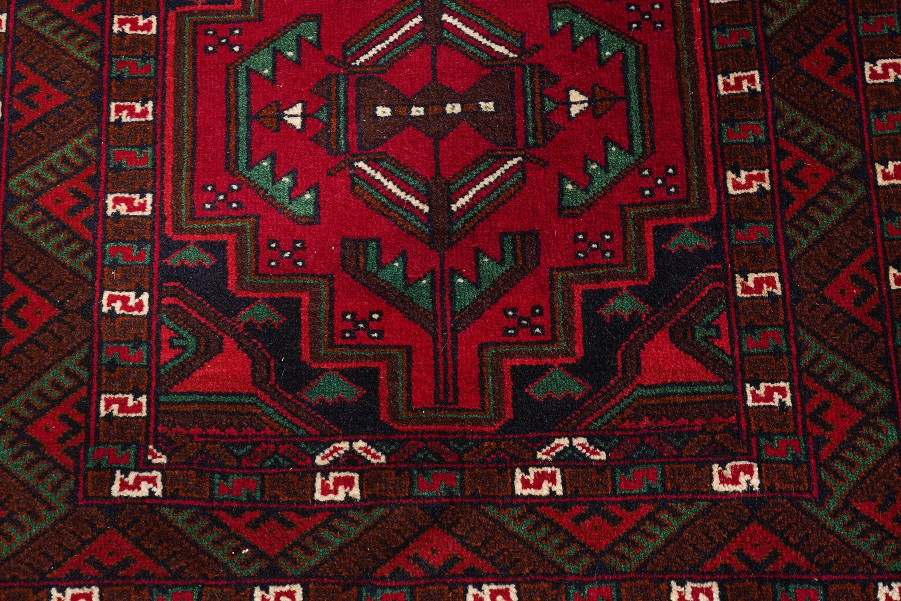 Four small Persian and Caucasian design rugs, comprising a Kazak rug with twin hooked medallions on a red ground, Baluchi rug with geometric motifs on a muted red ground, Shiraz rug with a central ivory and red medallion on a blue ground, and a Bokhara mat with four guls on a rose ground, each enclosed by geometric borders, largest 143cm x 88cm (4)