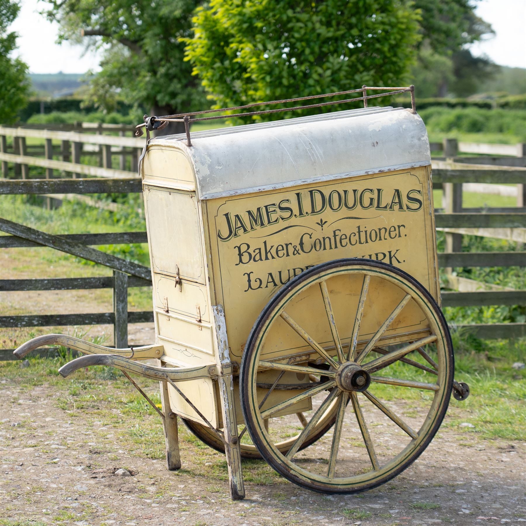 James I. Douglas, Baker & Confectioner, Laurencekirk Hand Drawn Delivery Cart

An attractive late 19th or early 20th century hand drawn baker's delivery cart, finished in cream and retaining its original hand painted advertising livery for James I. Douglas, Baker & Confectioner, Laurencekirk. The enclosed body features a curved roof with external luggage rail, rear access doors and internal shelving for the transport and delivery of bread, cakes and confectionery. Mounted on large wooden spoked wheels with iron tyres and fitted with shaped shafts for a single horse, this is a highly decorative and increasingly scarce example of a provincial tradesman's delivery vehicle, offering excellent display potential for collectors, museums, period interiors or commercial settings.

Features:
• Original hand painted signwriting for James I. Douglas, Baker & Confectioner, Laurencekirk
• Enclosed delivery body with curved roof and external luggage rail
• Rear opening access doors with internal storage compartments
• Original internal wooden shelving and racks
• Large wooden spoked wheels with iron tyres
• Shaped shafts for single horse traction
• Builder's mark for Geo. Roberson Ltd., Wallington
• Decorative cream painted finish with period lining and detailing
• Suitable as a display piece, museum exhibit or advertising feature

Dimensions:
Overall length: 170 cm
Body length: 104 cm
Width: 83 cm
Height: 150 cm

Wheel Diameter:
Wheels: 95 cm