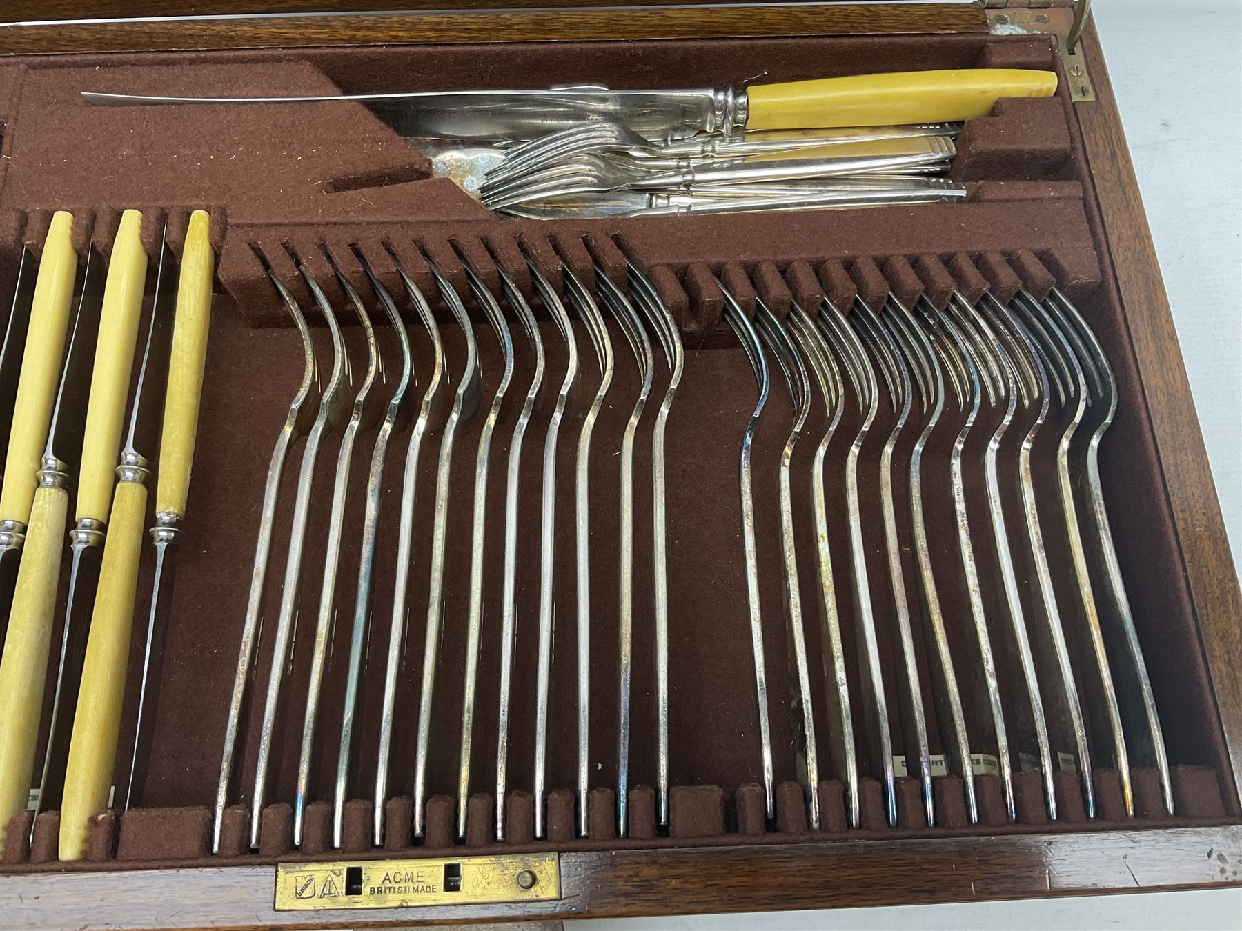 Elkington & Co part canteen of silver plated and stainless steel cutlery, to include simulated ivory handled examples, housed in oak and mahogany case, lock plate stamped 'Acme, British Made', W49cm D31cm H18cm