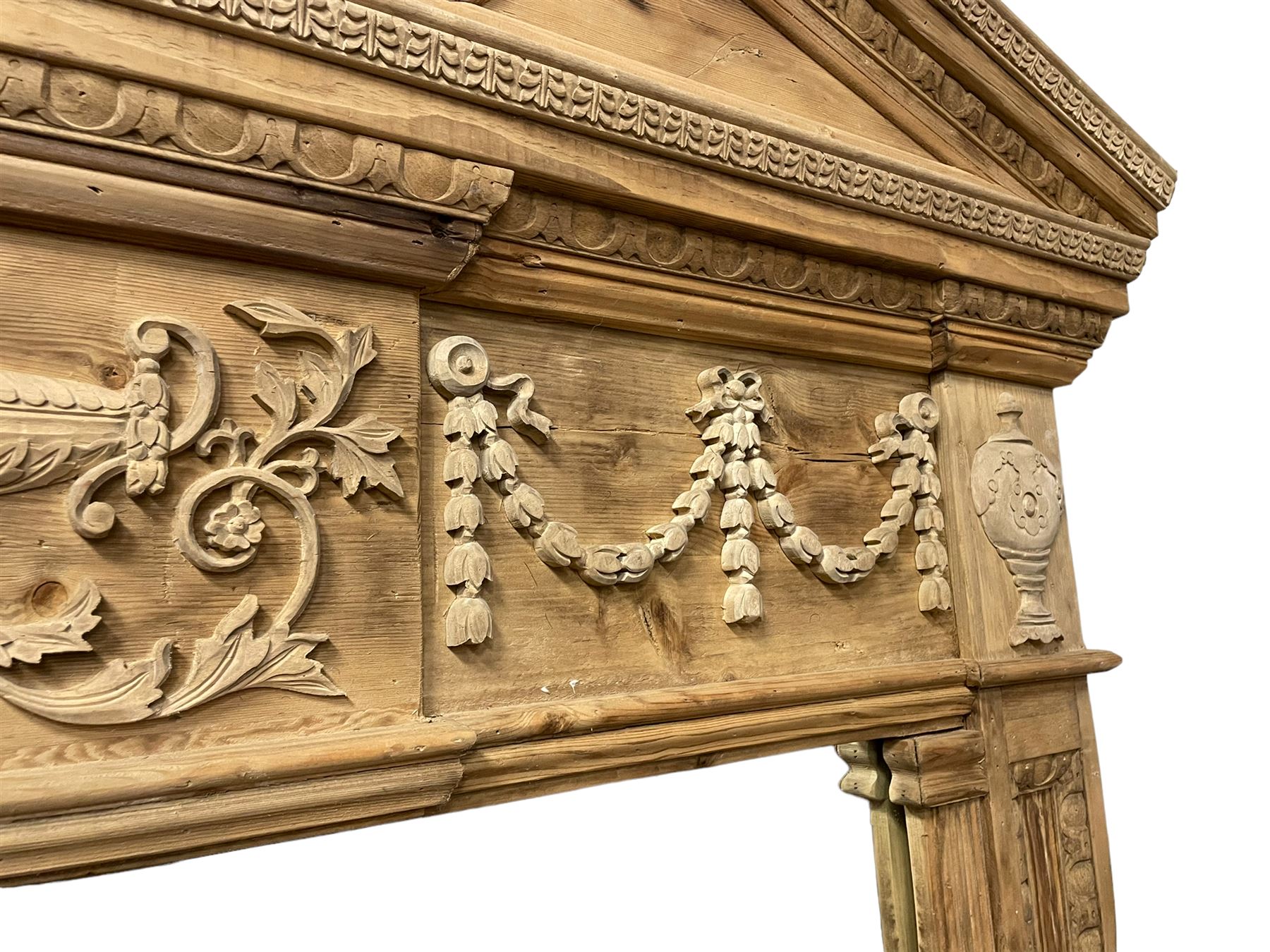 Large Adams design pine frame mirror, sloped broken arch pediment with central acanthus leaf carving, the frieze decorated with bell flower garlands and central kylix vase motif, large plain mirror plate flanked by panelled sides with egg and dart mouldings and reeded slip mouldings, on plinth base