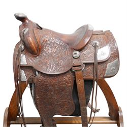 Keyston Bros (San Francisco) - 1930s/1940s 18’ American leather and silver mounted Western Parade saddle, the mahogany-tone leather body heavily hand-carved in a deep California Poppy floral pattern, surmounted by a ‘Bear Trap’ pommel fitted with an oval horn cap featuring a silver medallion of a cowboy on a bucking horse, further embellished with engraved sterling silver mountings, including large domed conchos, full-dress skirt corner plates, and a continuous cantle trim band, together with the associated girth, stirrups and leathers