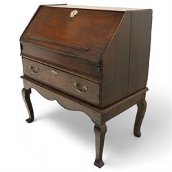 Early 18th century George I oak bureau on original stand, the fall front enclosing an arrangement of correspondence drawers and pigeonholes over central well, fitted with single long drawer below, the shaped apron over cabriole supports with pad feet