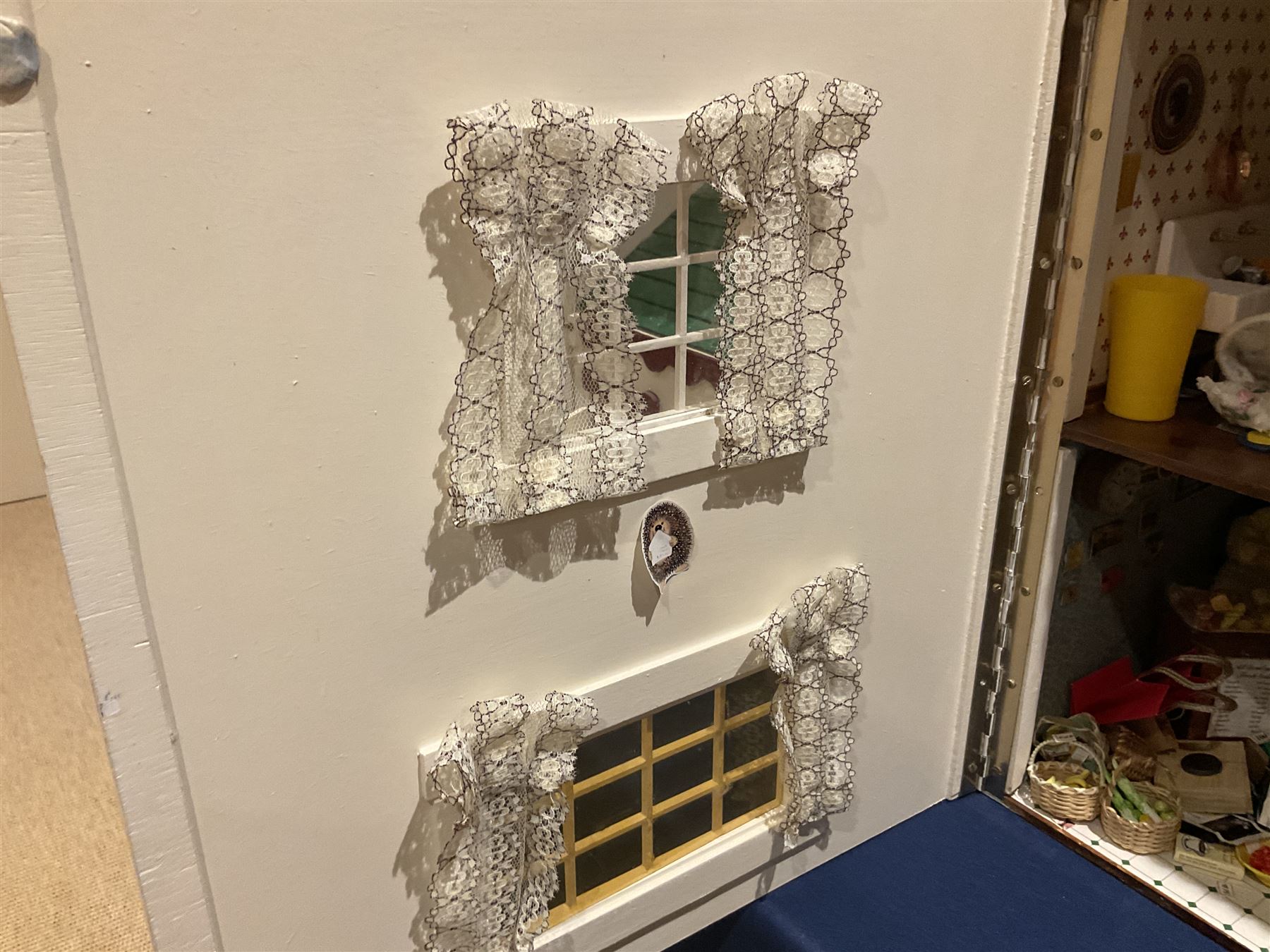 Seagull Pub - scratch-built wooden doll's house as a two-storey gable fronted public house painted in white green and maroon; the hinged front with ground floor veranda and window over opening to reveal two fully furnished rooms with dog-leg staircase and well stocked bar with bar-tender L31cm H62cm D37cm; together with Corner Shop and Dollies Pantry; a similarly painted scratch-built wooden two-storey flat-roofed doll's house as a well stocked ground floor grocery shop with stairs up to two further fully furnished rooms and more stairs giving access to a roof terrace L46cm H57cm D33cm (2)