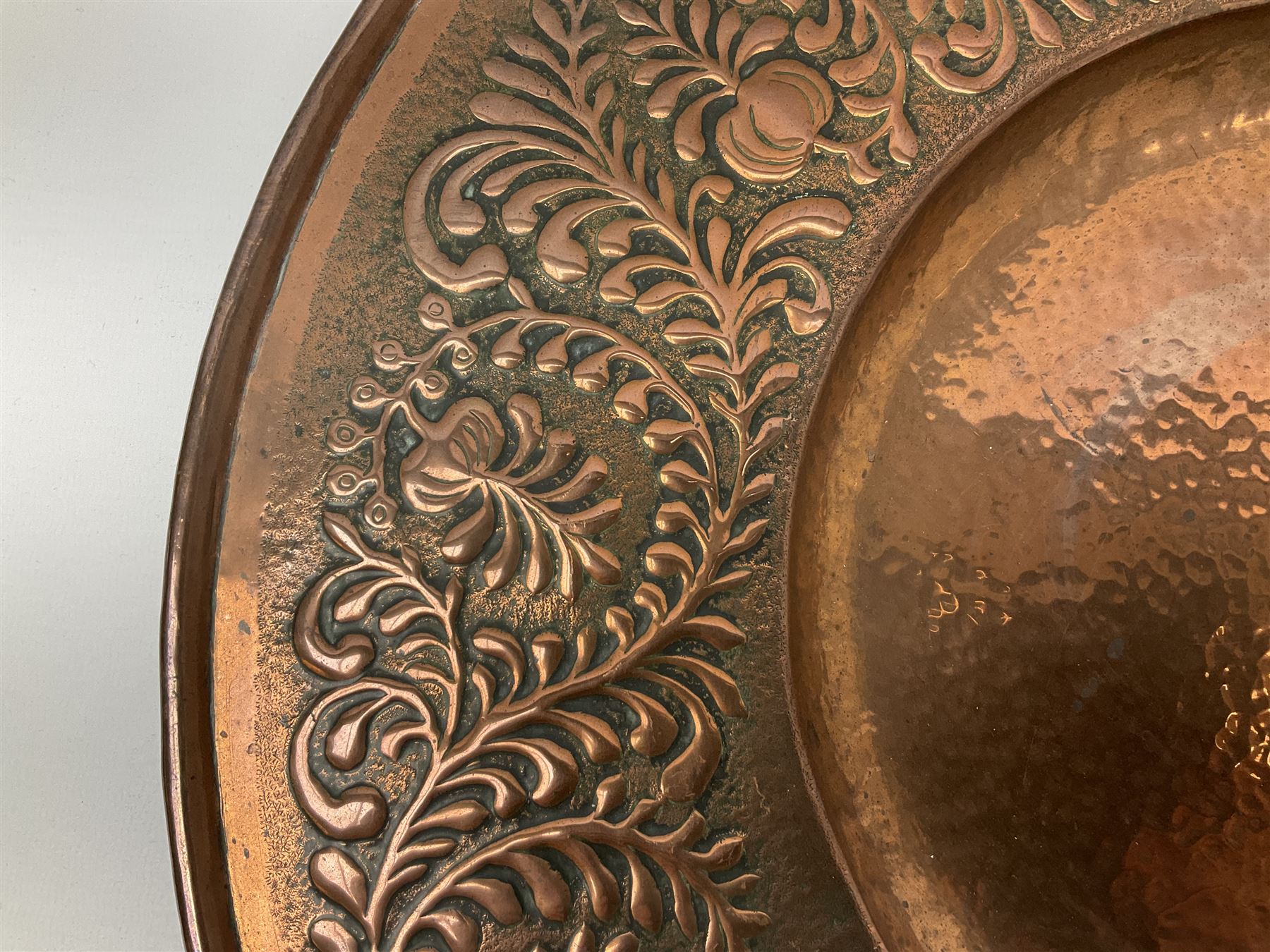 Arts and Crafts Keswick School of Industrial Arts copper charger, decorated with planished centre and repousse scrolling foliate tendrils to rim, D44cm
