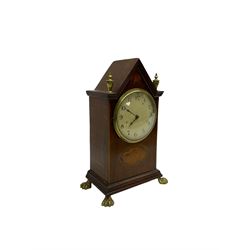 French - Edwardian 8-day mahogany inlaid mantle clock with a gable pediment and brass finials, oval inlay to the front and raised on brass paw feet, painted dial with arabic numerals and spade hands within a glazed bezel, timepiece movement with a lever platform escapement. With key.