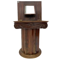 Victorian mahogany vanity unit in the form of a column, the scrolled top with hinged lid revealing mirror, wash bowl and toiletry dishes, on scalloped cylinder pedestal with single door, the interior fitted with shelf