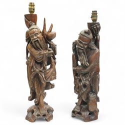 Pair of Chinese hardwood table lamps, carved as two elderly figures, the first holding a f...