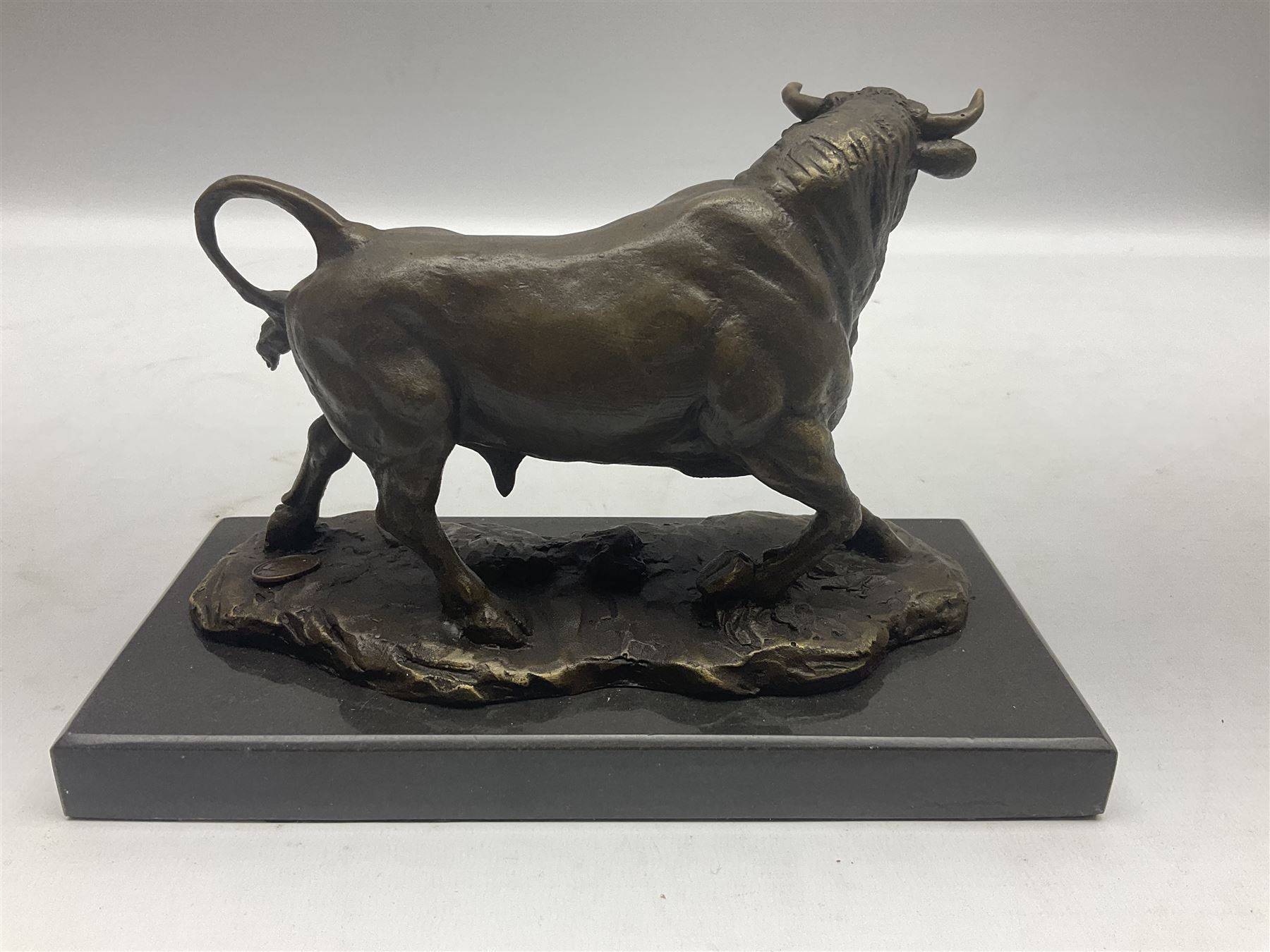 Bronze figure, modelled as a prancing bull, upon a naturalistic base signed Mils and with foundry mark, raised upon a rectangular marble base, overall H14cm