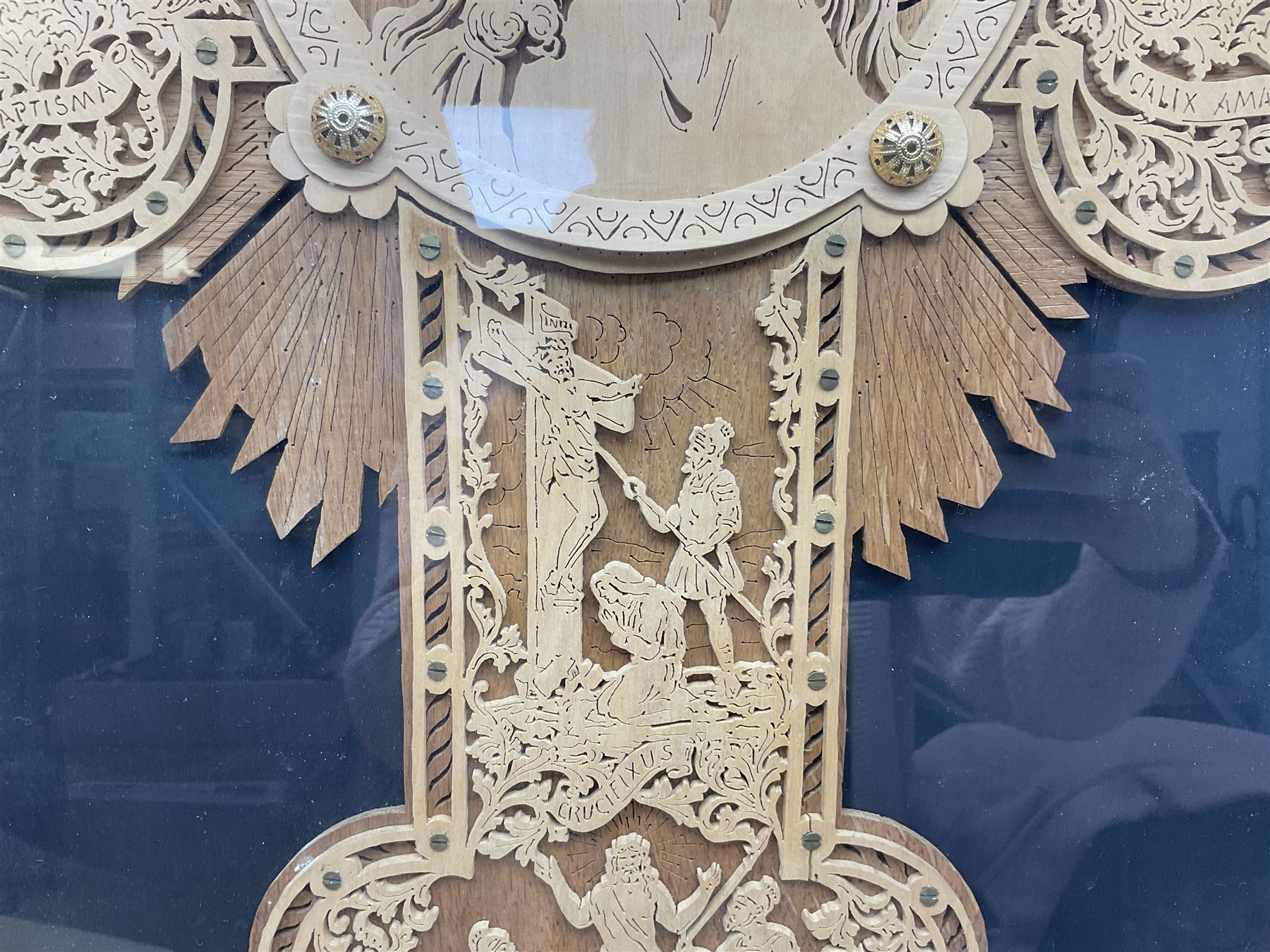 Cork carving of a religious cross depicting intricate scenes of various religious figures and motifs amongst trees and foliage, with central circular panel of Jesus Christ, in glazed frame, H95cm