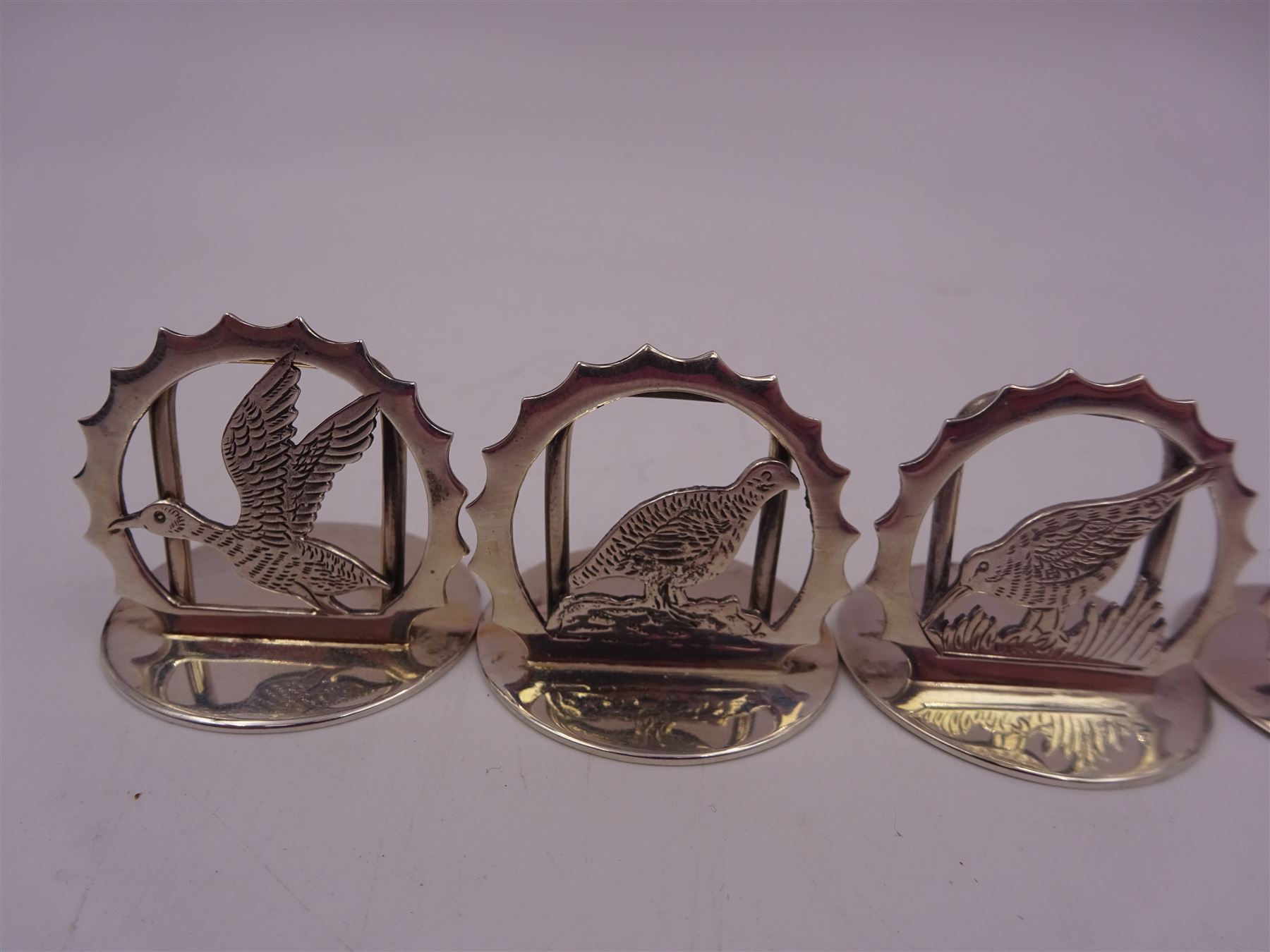 Set of six modern silver place card holders, each of circular form with pierced depictions of a partridge, spaniel, pheasant, stag, woodcock and duck, hallmarked J A Campbell, London 1985, contained within a velvet and silk lined fitted case, H3cm