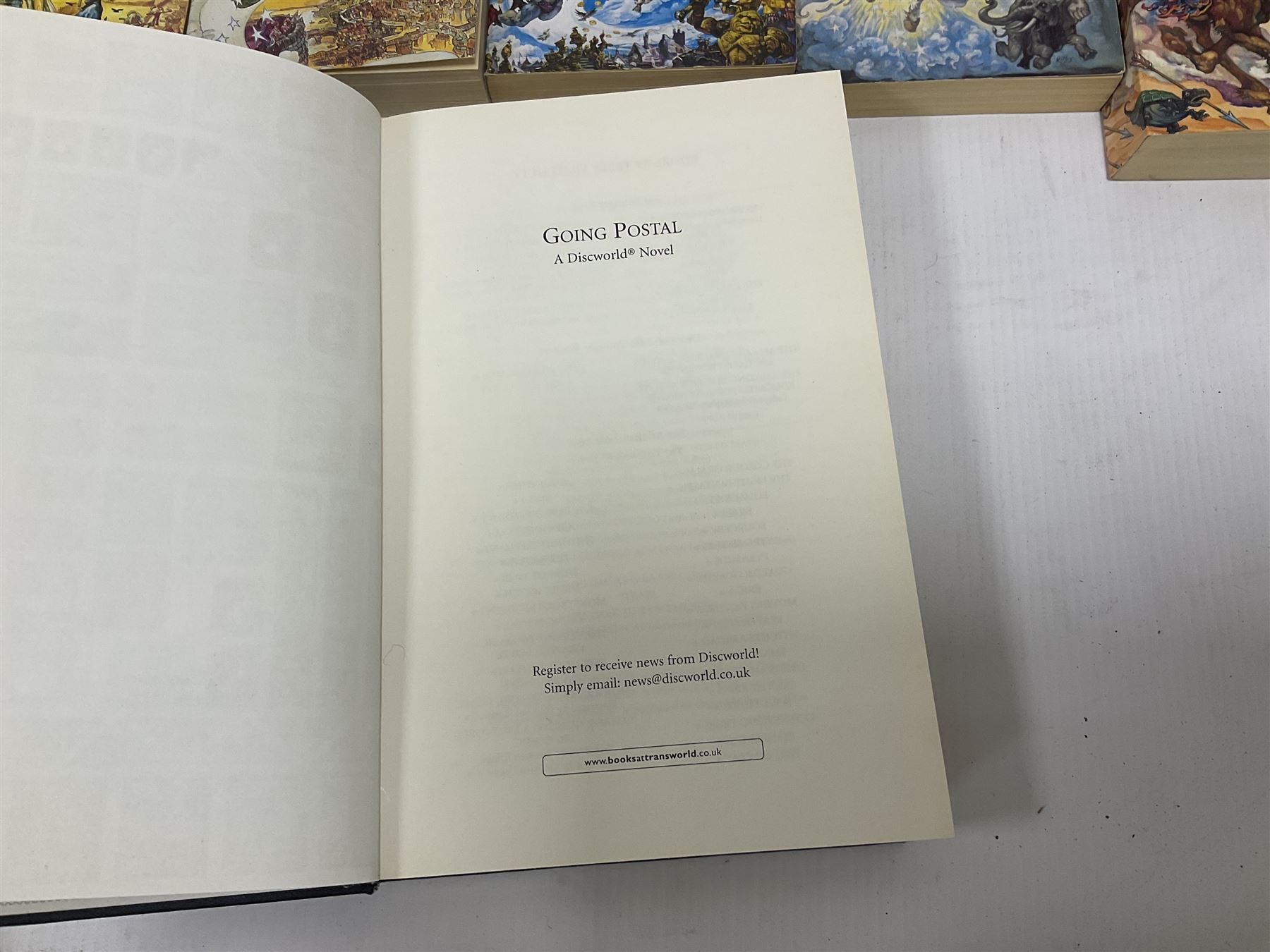 Collection of books by Terry Pratchett, of mostly Discworld interest, to include hardback edition of Going Postal, and further books such as Men at Arms, Sourcery, Small Gods etc 