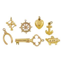 Six 9ct gold pendant / charms including wishbone, key, pig, anchor, ships wheel and heart and an 18ct gold atomic cube pendant /charm