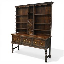 19th century Jacobean Revival oak dresser and rack, the upper section with open shelves and central cupboard, flanked by bobbin moulded uprights, the base fitted with three carved drawers with brass ring handles, raised on turned supports united by stretchers