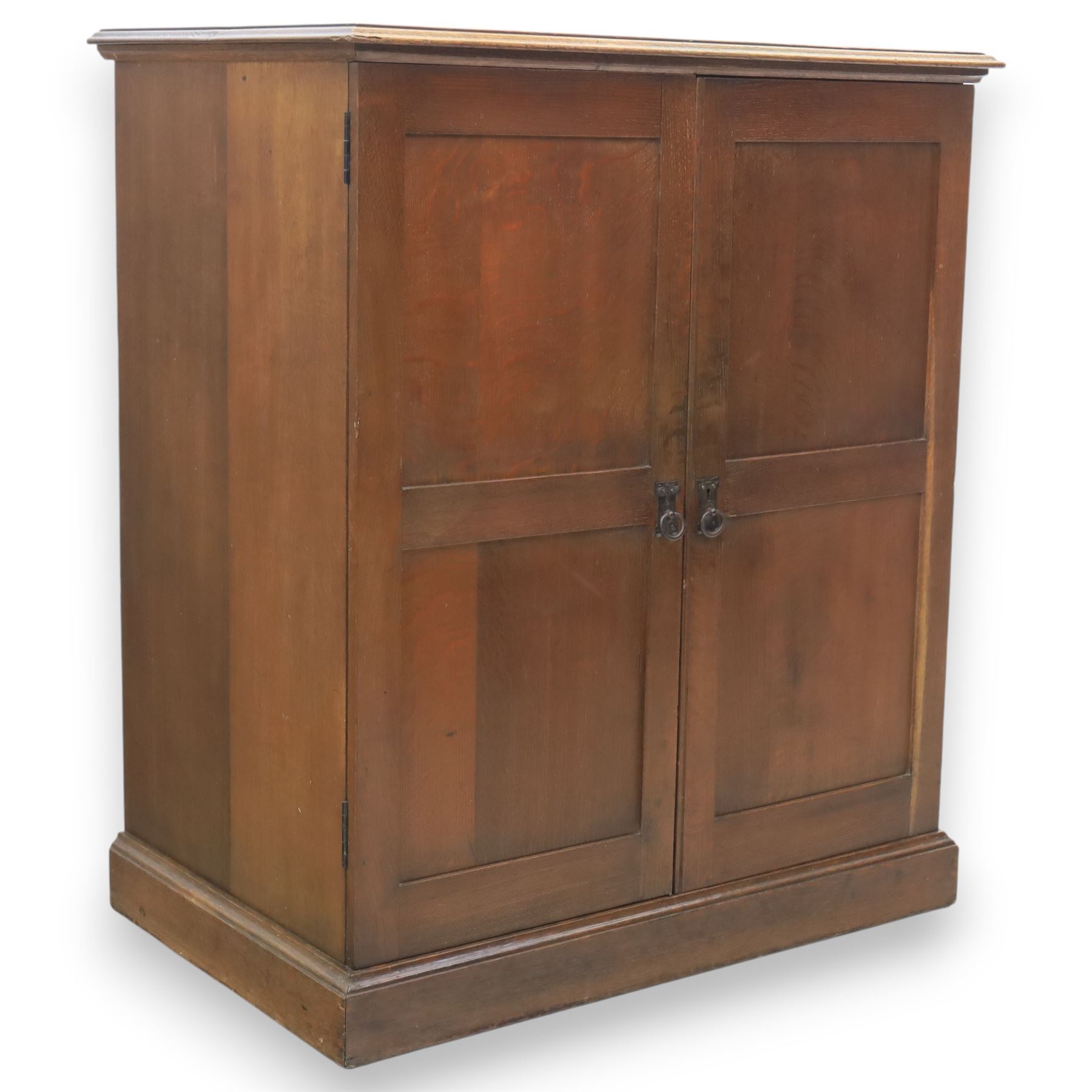 20th century oak Arts and Crafts fitted collector's cabinet, twin panelled doors with metal door pulls, enclosing a fitted interior, on a moulded plinth base