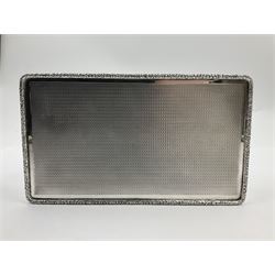 1920's silver table cigarette box, of rectangular form with engine turned decoration to the exterior, the hinged cover with central vacant rectangular panel and raised foliate rim, opening to reveal a gilt interior with later plush lining, hallmarked Charles Henry Dumenil, London 1923, H3.5cm L14.5cm D8.5cm