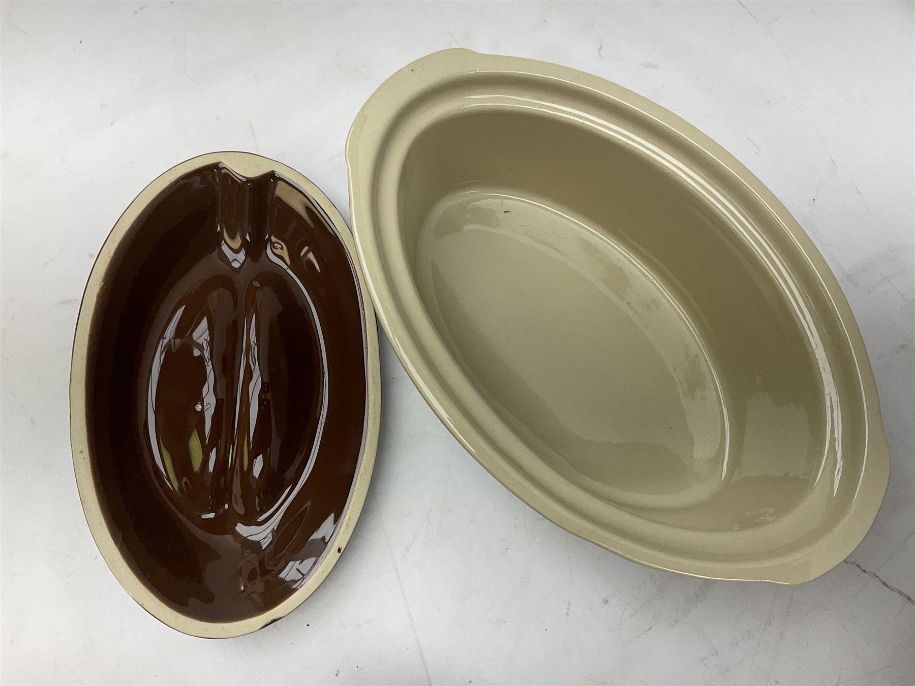 Emile Henry covered casserole dish of oval form in two tone brown and cream, no. 03.06, together with cast iron Nomar twin handled lidded casserole dish of oval form in navy, and other ovenware including Flintware ICTC, largest L35cm