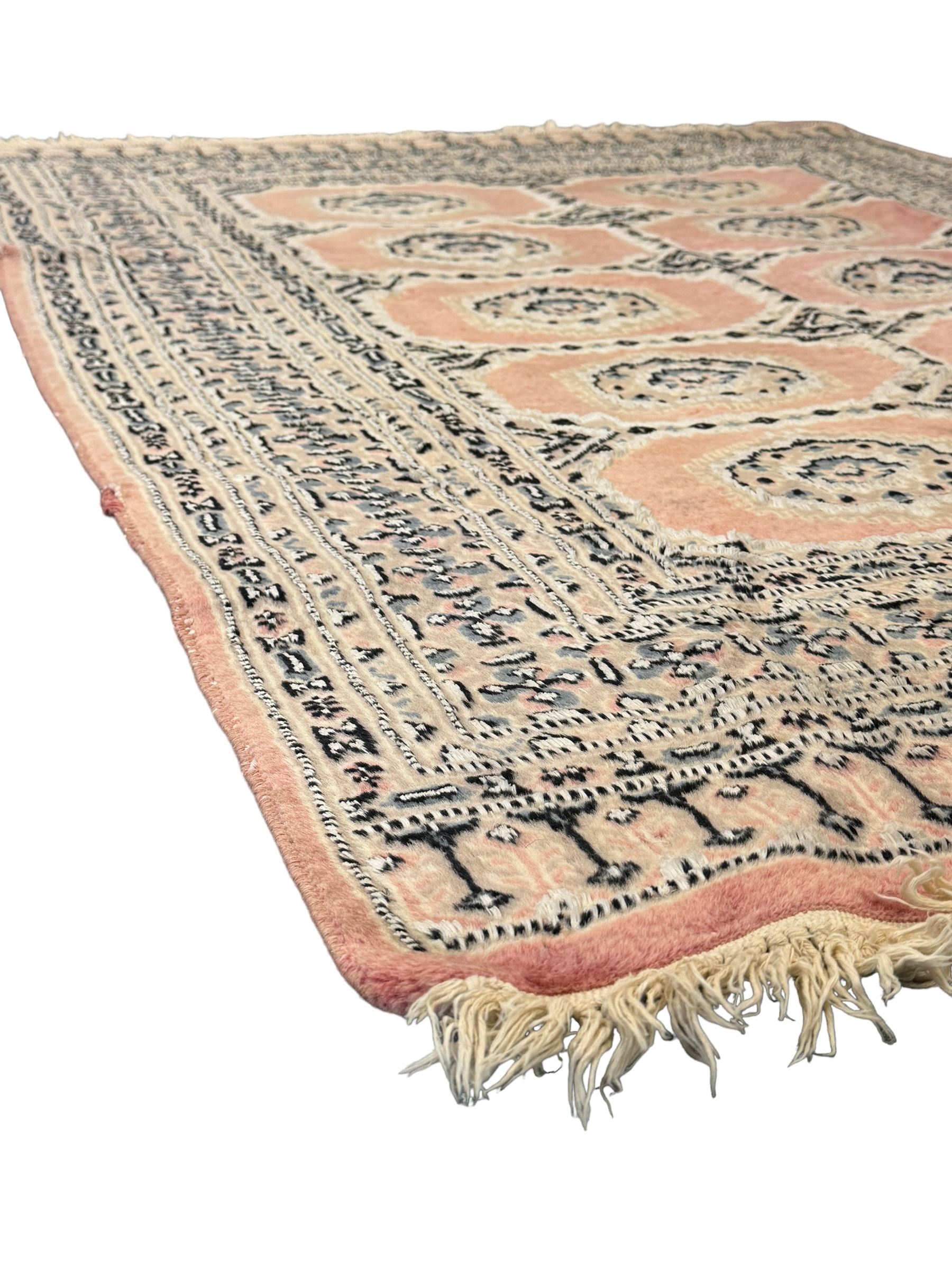 Persian design pale pink ground rug, the field divided into panels and decorated with Gul motifs, wide multi-band border with geometric patterns 