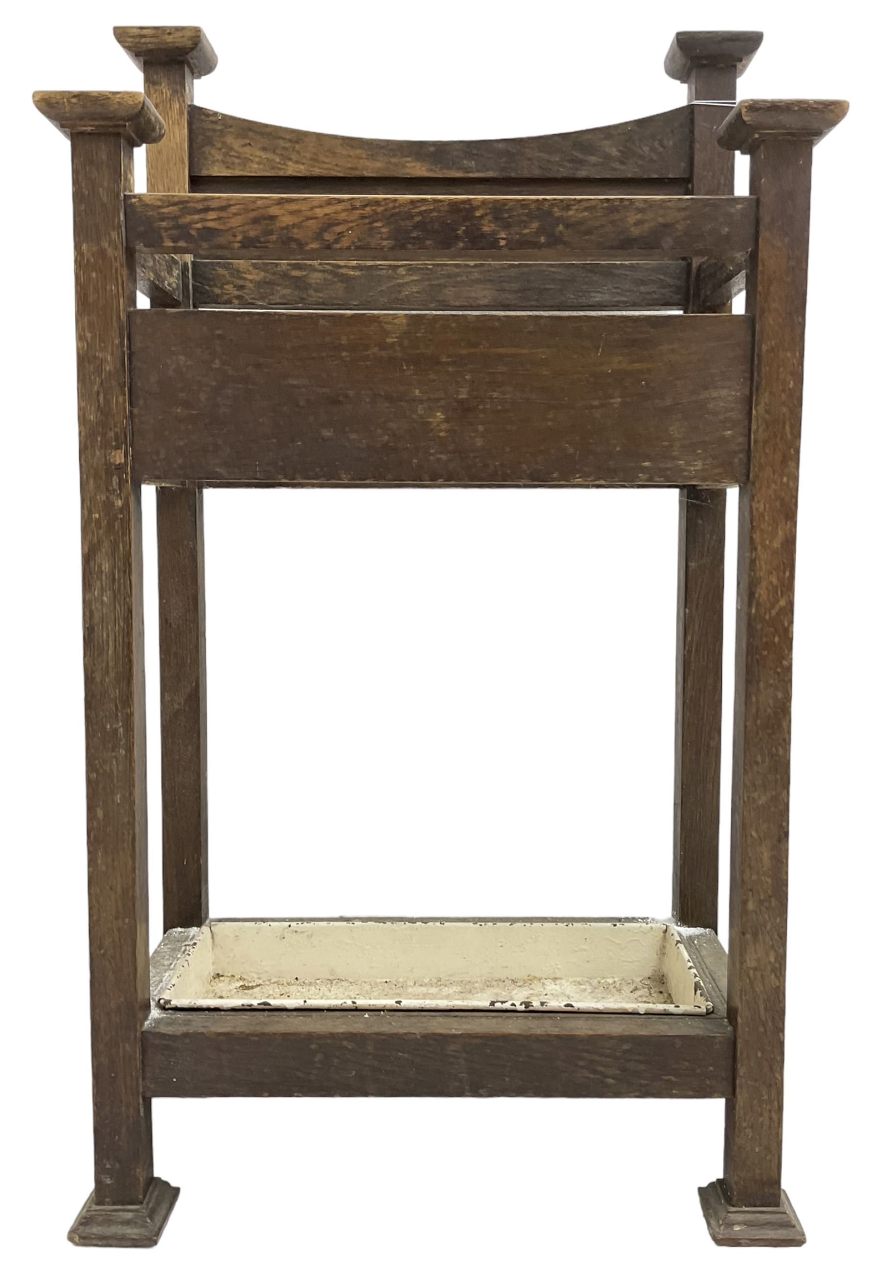 Early 20th century Arts & Crafts oak stick stand, panelled back over three divisions, fitted with metal drip tray, on square supports