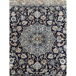 Central Persian Nain carpet, the deep blue field with finely drawn scrolling palmettes and flowering vines around a central ivory and sky blue rosette medallion, enclosed by an ivory border of interlaced floral arabesques and lotus forms between multiple guard stripes, from the region of Nain