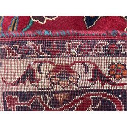 Persian rug, red ground field decorated with stylised flower heads and bird motifs, floral scrolling border