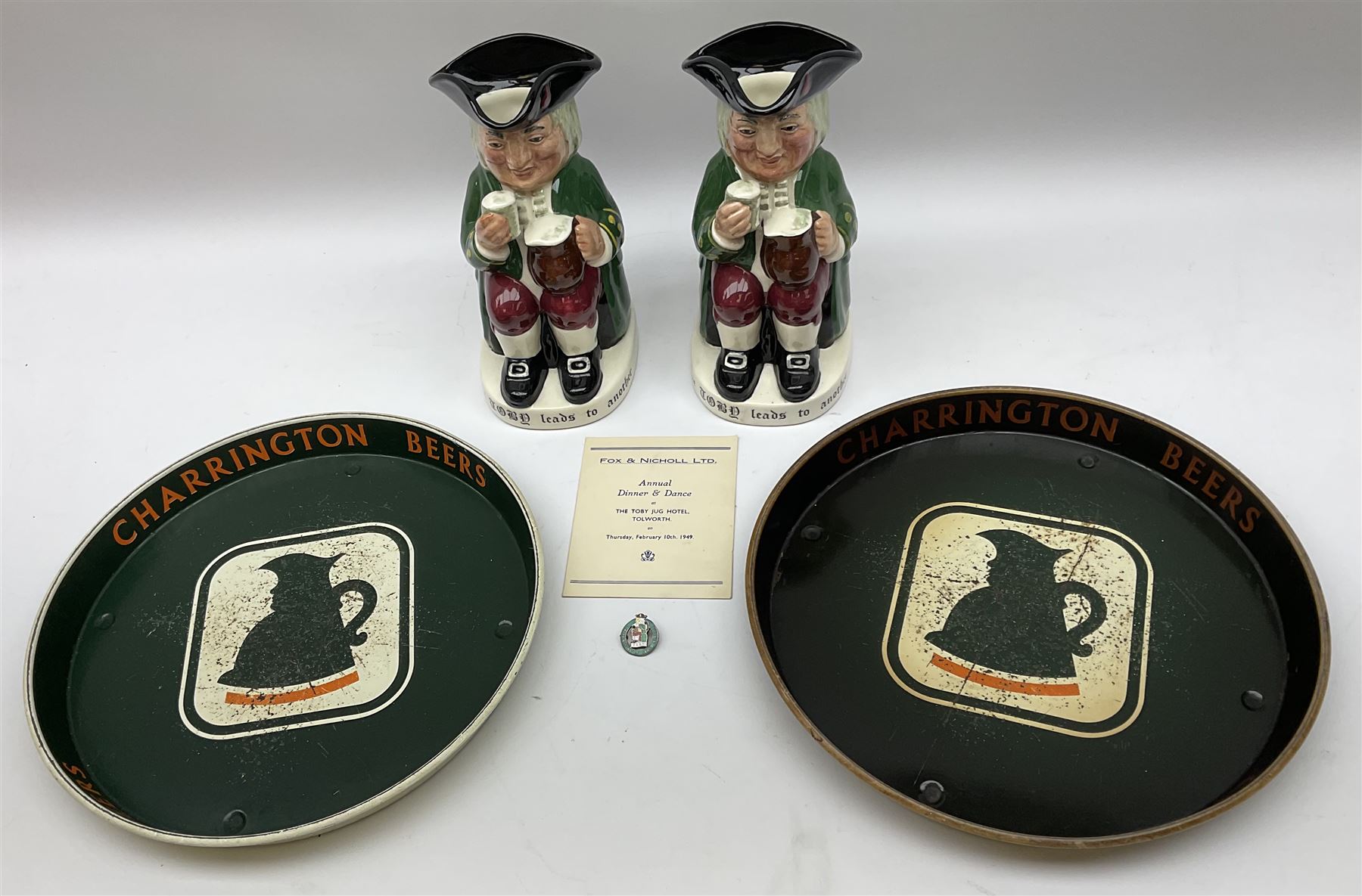 Pair of Royal Doulton Toby Ale Jugs, produced in 1934 for Charrington Ales, together with two circular metal serving trays advertising Charrington brewery, a Charrington badge awarded for 25 years of service and a 1949 menu Fox & Nicholl Ltd annual dinner dance at the toby jug hotel.  