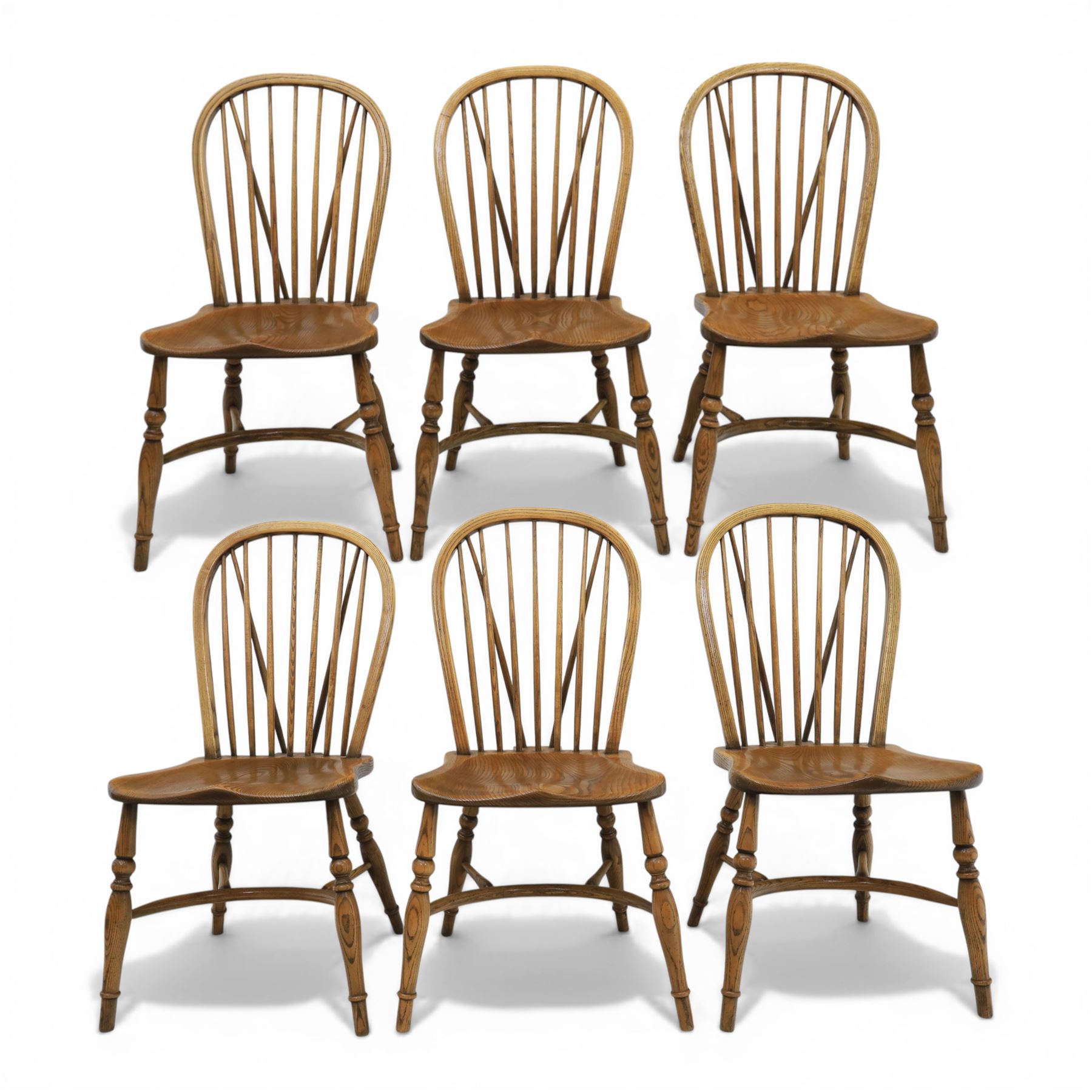 Traditional elm and beech Windsor dining chairs, each with hoop back and turned spindles over a shaped solid seat fitted with loose floral upholstered cushions, raised on turned tapering supports united by crinoline stretchers