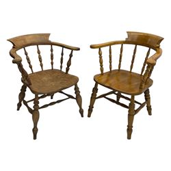 Late 19th century elm smoker’s bow armchair, curved top rails over turned spindle backs, shaped seats, raised on turned legs united by turned stretchers; together with a similar smoker’s bow armchair (2)