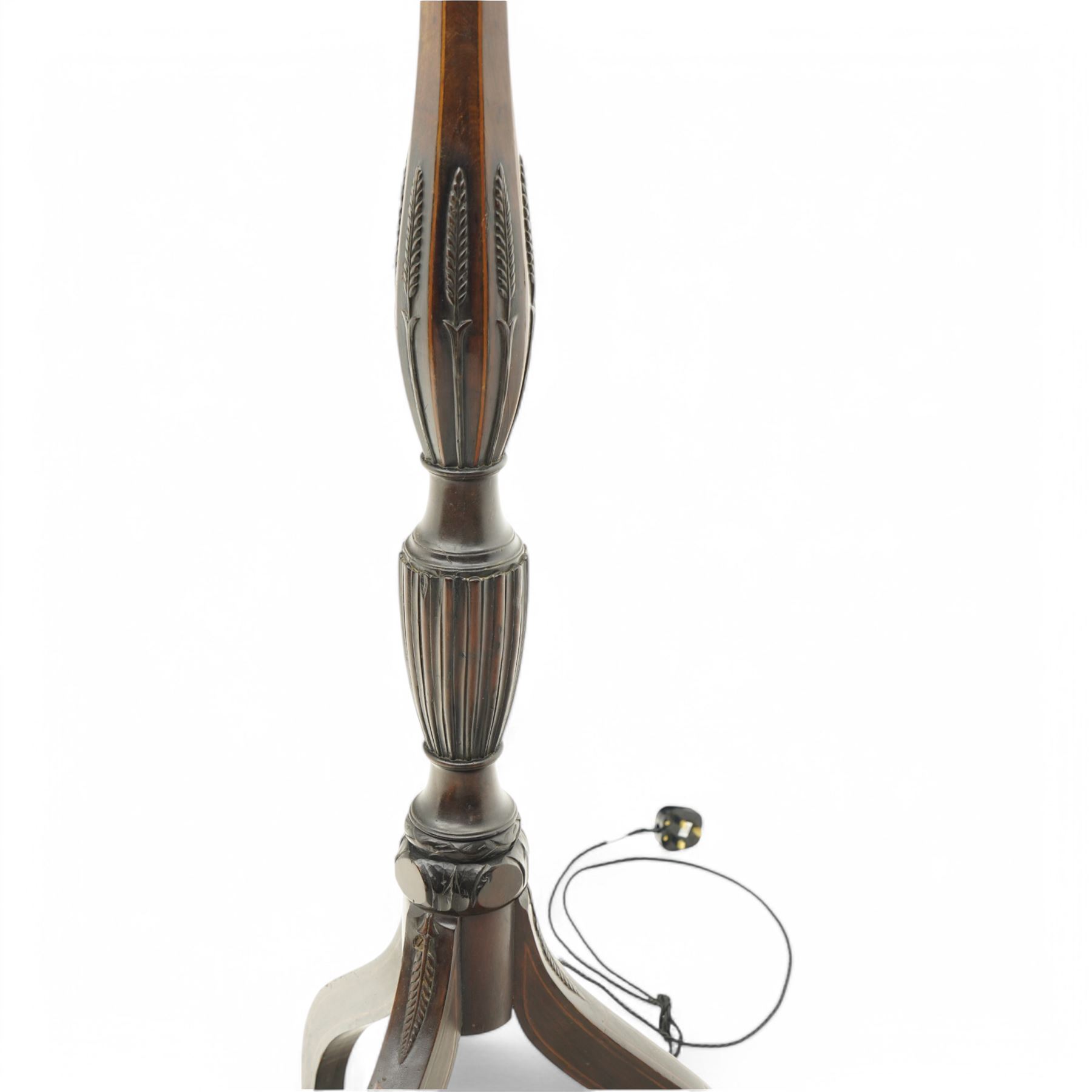 Hepplewhite design mahogany standard lamp, faceted bulbous column decorated with stylised leaf carvings, on three splayed supports 