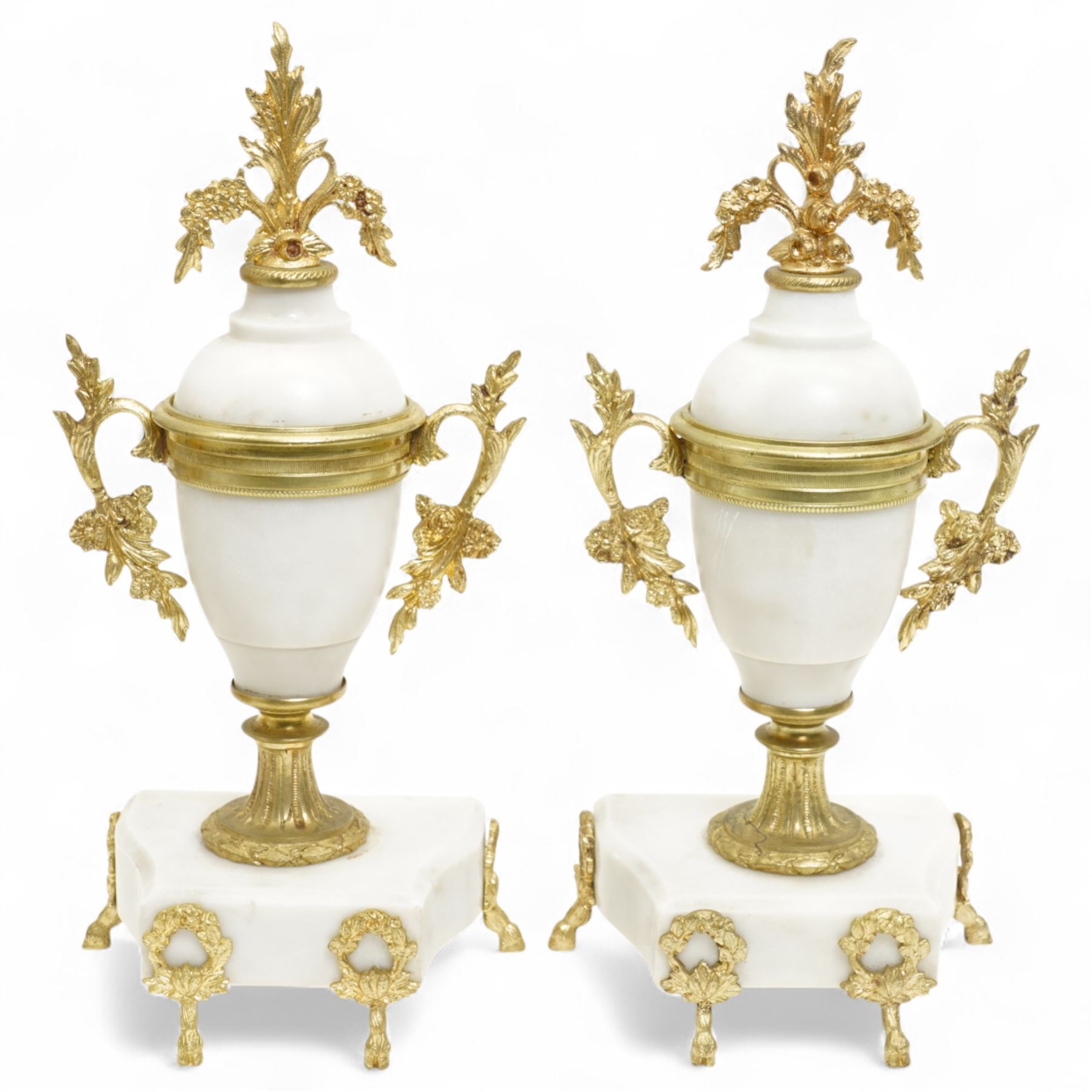 French-Early 20th century 8-day white marble and gilt metal striking portico mantle clock and garniture, Parisian drum movement with a white enamel dial, Arabic numerals and garland swags, two train countwheel striking movement sounding the hours and half hours on a bell. With a matching pair of conforming urns with gilt mounts. 
