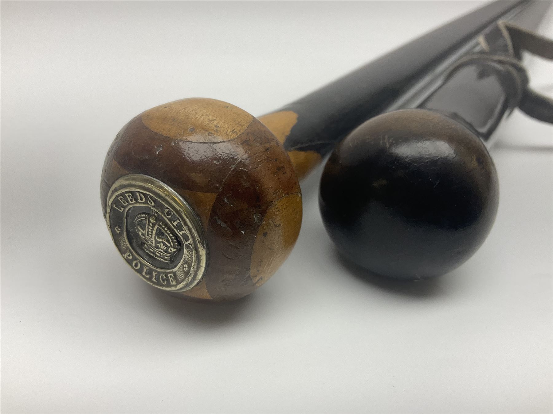 Two ebonised walking sticks, one with 'Leeds City Police' embossed top, tallest H92cm