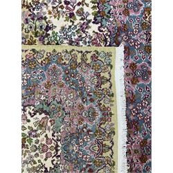 Central Persian Kirman ivory ground rug, decorated all-over with flower heads and trailing foliage, shaped pink and blue ground borders with olive green outer band