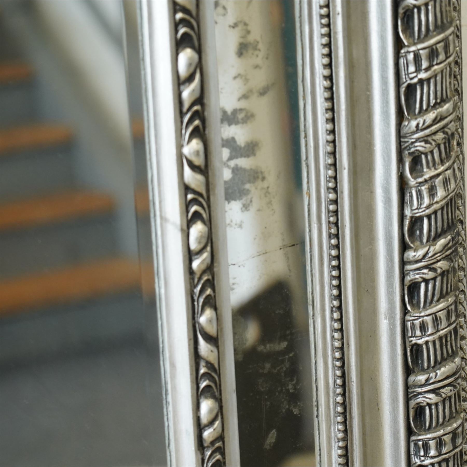 Impressive Baroque Revival mirror in antique silvered finish, the pierced cartouche shell pediment flanked  by C-scrolls and flower heads, the outer frame with ribbon-twist motifs throughout, the central arched bevelled plate surrounded by further rectangular mirror panels with cartouche mounts