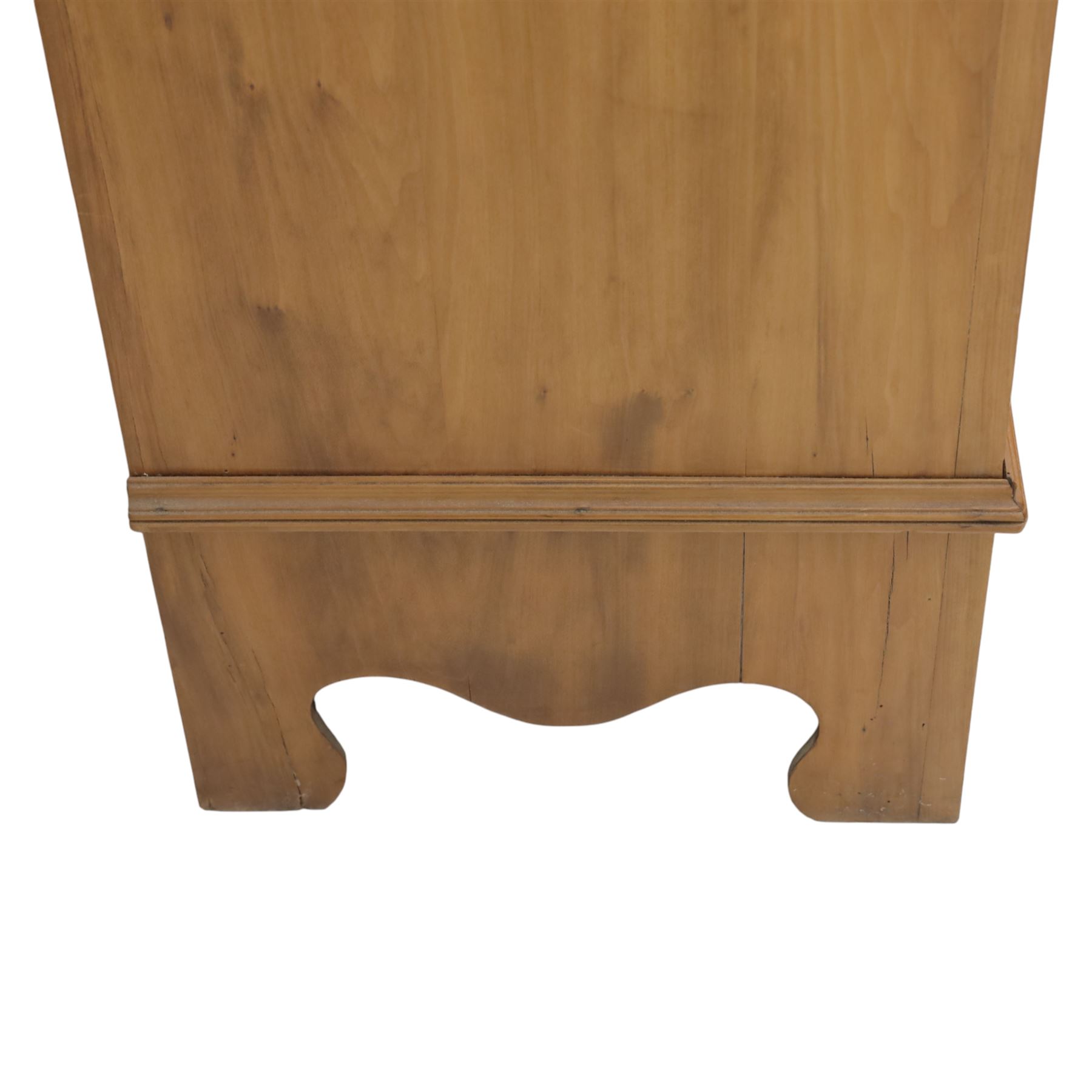 Edwardian stained pine dressing chest, the moulded top over three graduating drawers with pressed brass handles, shaped apron and bracket feet, the mirror back with rectangular plate on pivot supports, flanked by pierced Gothic style uprights with small corner shelves