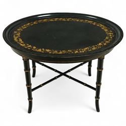 Regency style oval toleware tray table, the black lacquered top with gilt floral decoratio...