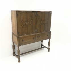  Early 20th century oak cocktail cabinet, four doors enclosing shelves above two drawers, turned supports joined by stretcher, label on back 'Rowntree's, Scarborough - York', W122cm, H145cm, D46cm  