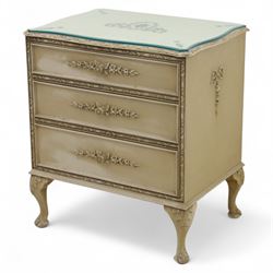 French design cream painted three drawer commode, shaped front with floral garland appliqués, fluted uprights and acanthus carved cabriole legs terminating in scroll feet