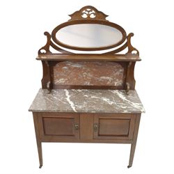 20th century mahogany marble topped washstand, rectangular veined grey marble top over two panelled cupboard doors with ring handles, raised on square tapering supports terminating in castors, the rear fitted with shaped back and oval swing mirror within a scroll cut frame surmounted by pierced cresting