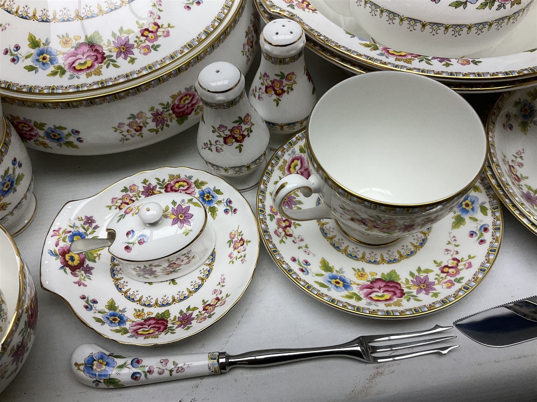 Extensive Royal Grafton Malvern pattern tea and dinner wares, comprising twelve dinner plates, six smaller plates, coffee pot, two teapots, two cake plates, eight teacups and ten saucers, six coffee cups and six saucers, two open sucriers, twin handled lidded sucrier, jug, lidded mustard pot and condiment jar, lidded tureen, two circular twin handled vegetable tureens, sauce boat and stand, oval and circular serving plates, salt and pepper shakers, breakfast cup and two saucers, further large cup and saucer, eighteen tea plates of various shapes, six side plates, six cereal bowls and six further bowls, shell dish and dish of square form, fork and knife, together with a hallmarked silver condiment spoon