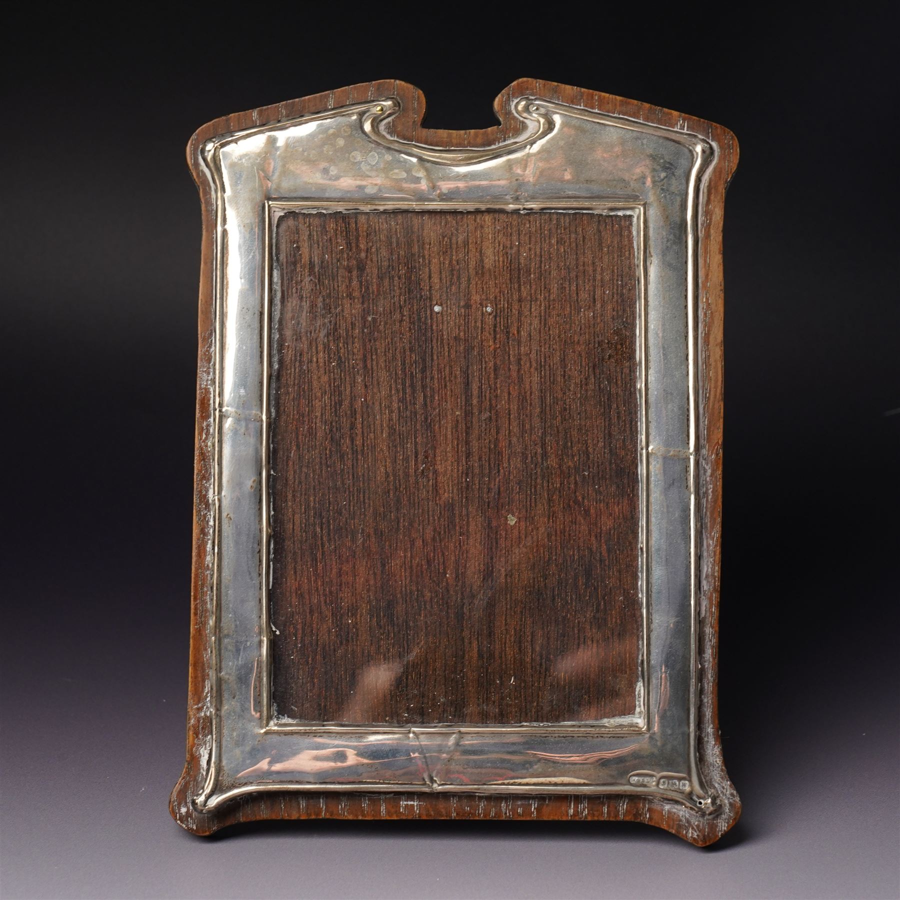 Embossed silver photograph frame London 1985 aperture 12.5cm x 8.5cm, another with scroll top Birmingham 1921 13cm x 9cm and a circular frame Birmingham 1909 6cm