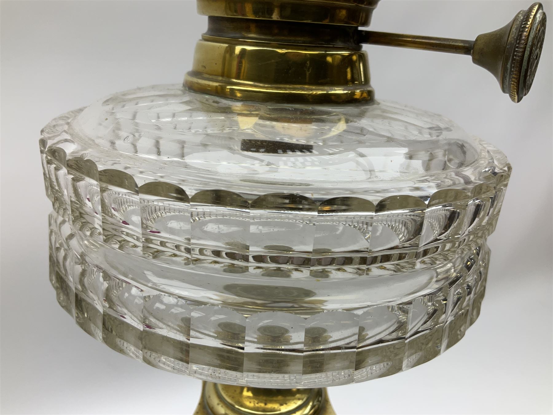 Victorian brass oil lamp, the square stepped base leading to a Corinthian column supporting a part slice cut clear glass reservoir, burner, clear glass chimney and foliate etched glass shade with amber rim, overall H80cm