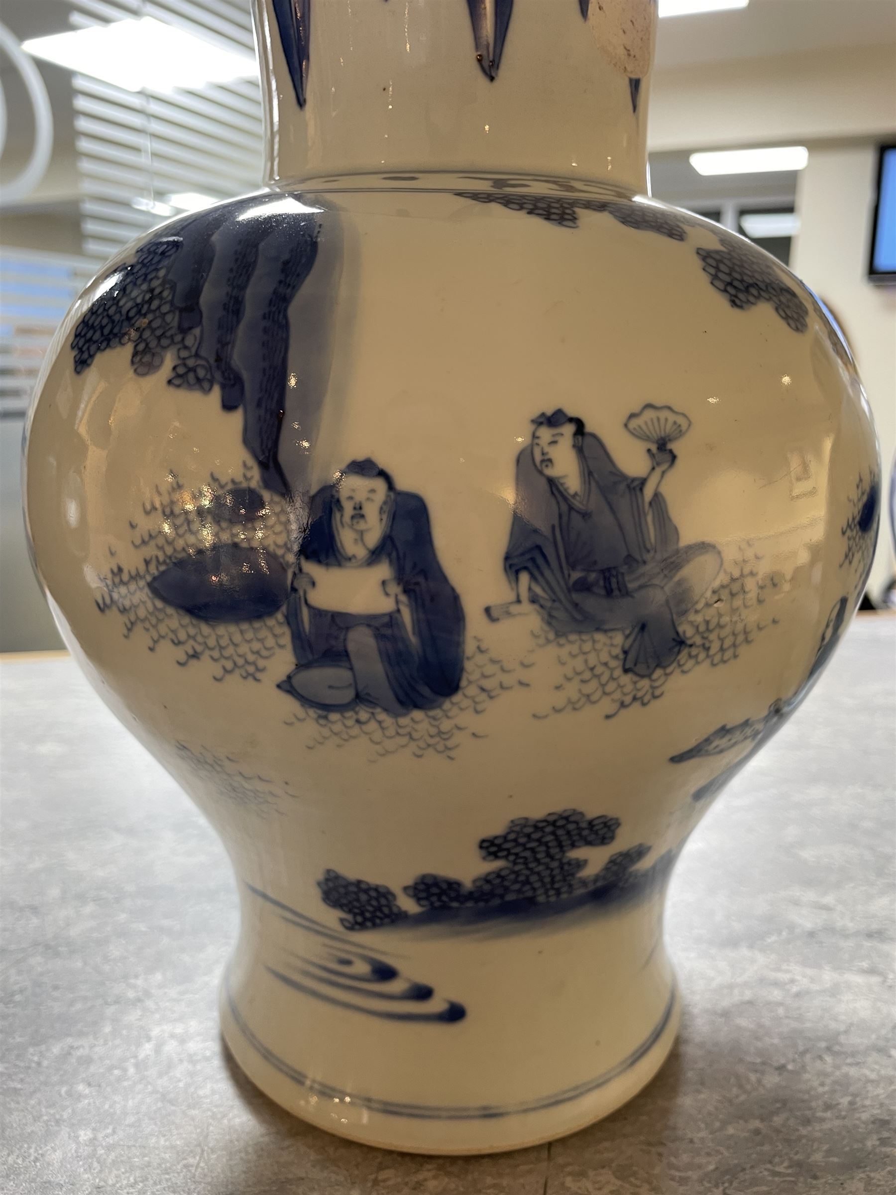 Pair of Chinese Kangxi blue and white porcelain vases, each of baluster form, painted with an outdoor scene containing figures seated upon the ground reading scrolls and holding fans, willow and bamboo tress, rock work and water, H27cm